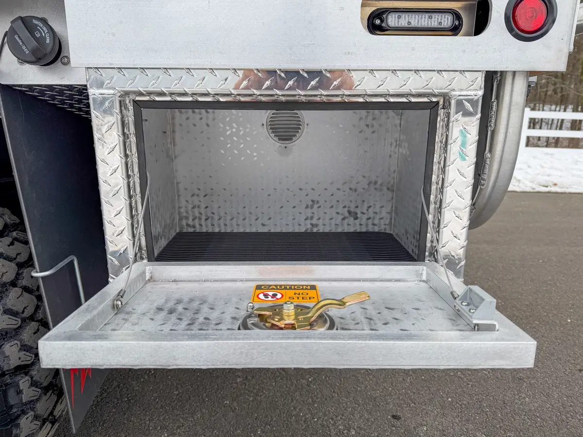 Open lower side box near rear wheel with textured floor.